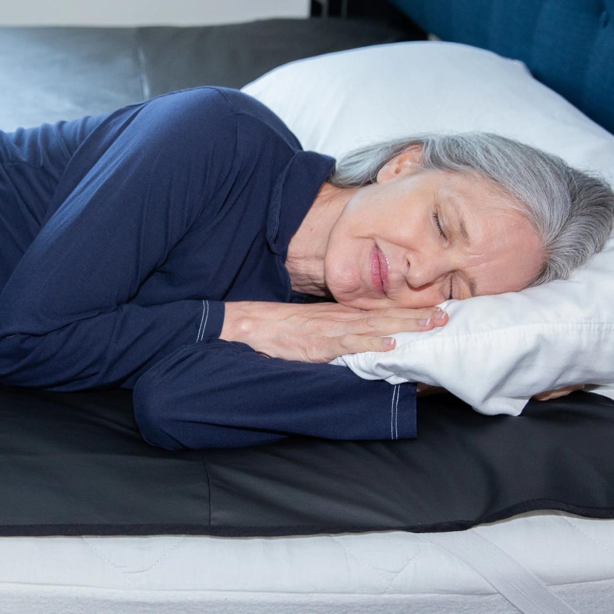 A bed made up with an Earthing mattress cover, fitted sheet folded back