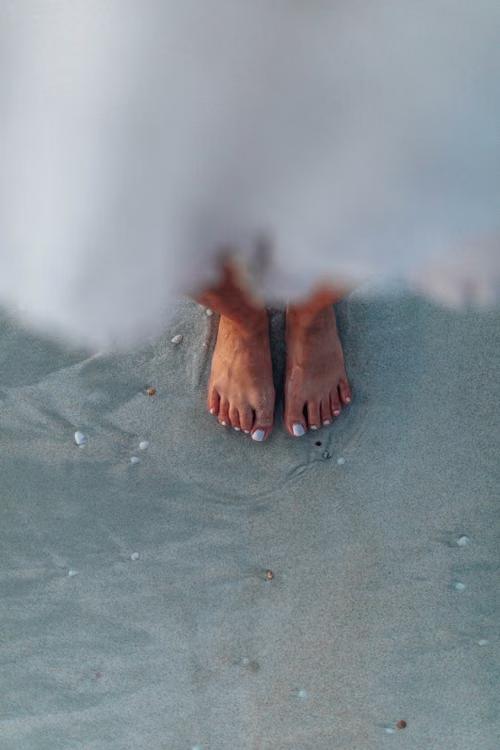 Bare feet at the waterline on wet sand