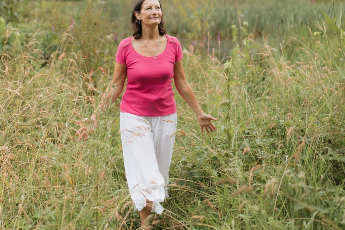 A woman walking barefoot through tall meadow grass on a summer day